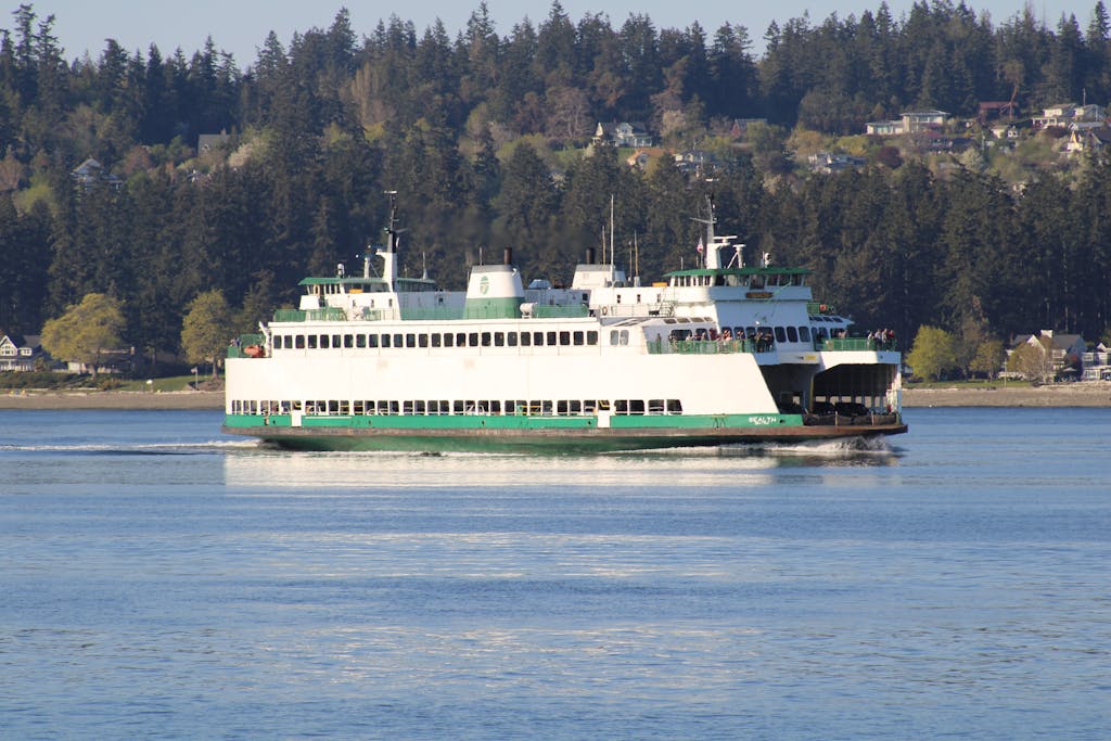 A Washington State Ferry sailing on the calm waters near Port Orchard, with a forested landscape in the background.